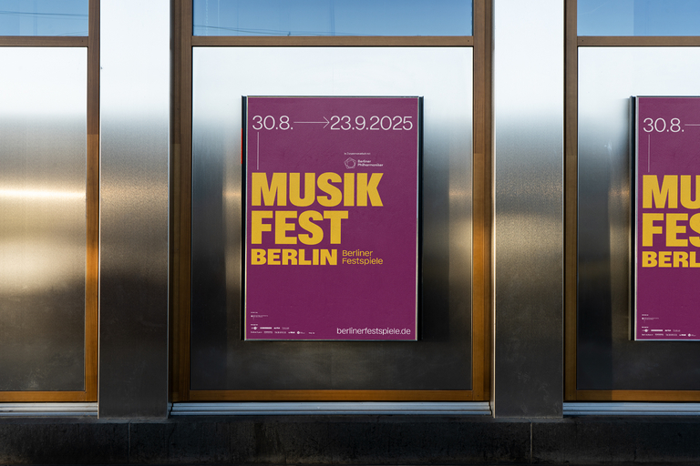 Plakat zum Musikfest Berlin 2025 mit gelber Typografie auf violettem Hintergrund, angebracht an einer Glasfassade. Das Plakat zeigt die Festivaltage 30. August bis 23. September 2025.