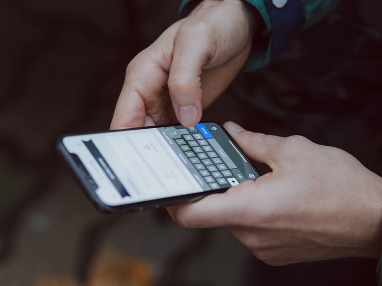 Symbolbild leichte Sprache: Freestocks on Unsplash. . Zwei Hände halten ein Smartphone. es wird getippt.