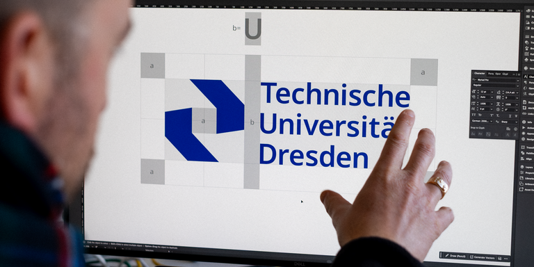 Eine Person sitzt vor einem Bildschirm und zeigt auf das Logo der Technischen Universität Dresden