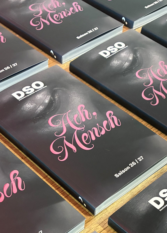 Viele dicke Programmhefte für das Deutsche Sinfonie Orchester DSO Berlin liegen gleichmäßig angeordnet auf einem Tisch aus